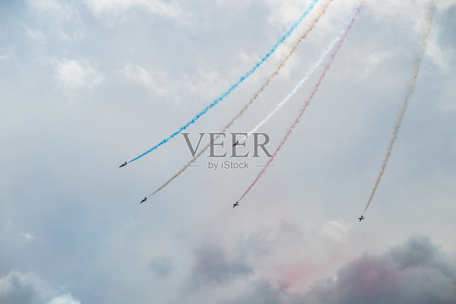 特技飞机在天空中表演五彩缤纷的烟雾轨迹。照片摄影图片