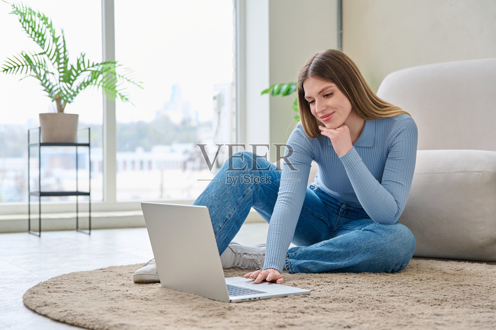 年轻女性坐在家里的地板上使用笔记本电脑照片摄影图片