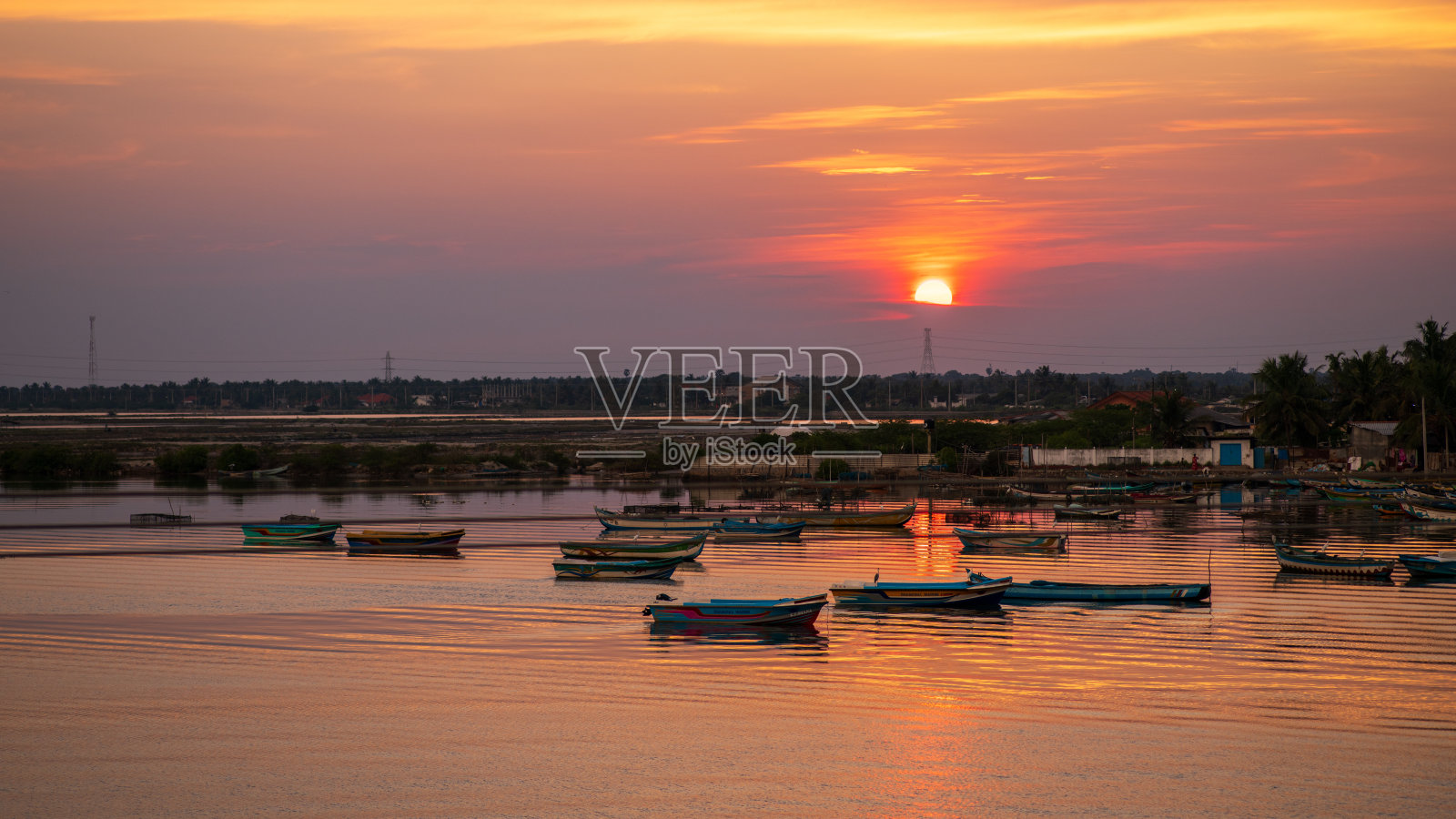 壮观的日落照亮了斯里兰卡曼纳尔的港口。五彩斑斓的渔船轻轻漂浮在金色的水面上。照片摄影图片