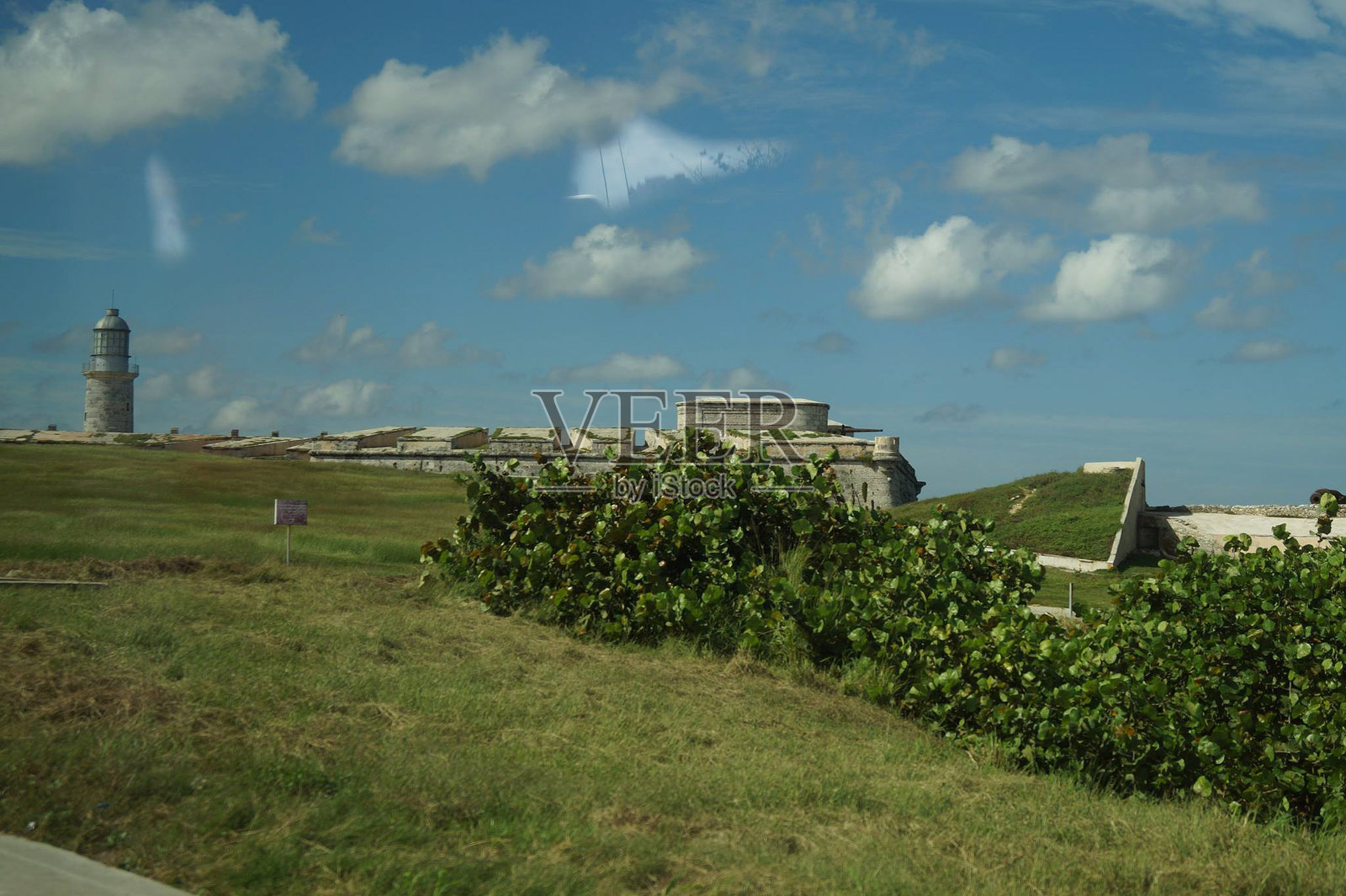 历史悠久的海岸防御工事俯瞰碧蓝的海水，阳光明媚，云朵点缀其间。照片摄影图片