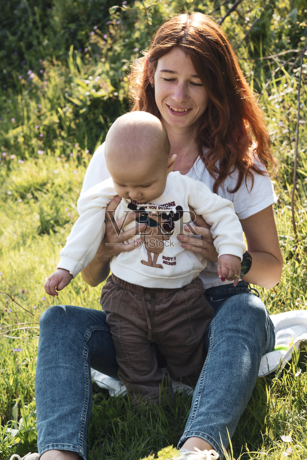 父母在绿草坪上引导宝宝迈出第一步照片摄影图片