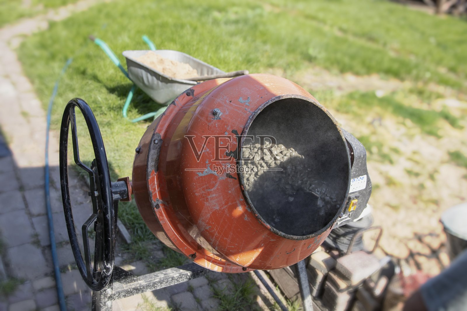 户外花园附近的水泥搅拌机正在施工中，搅拌新鲜混凝土照片摄影图片