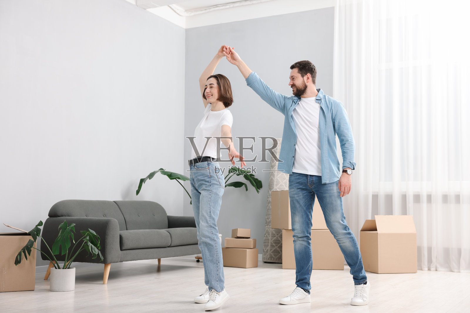搬家日。快乐的情侣在他们的新家里跳舞照片摄影图片