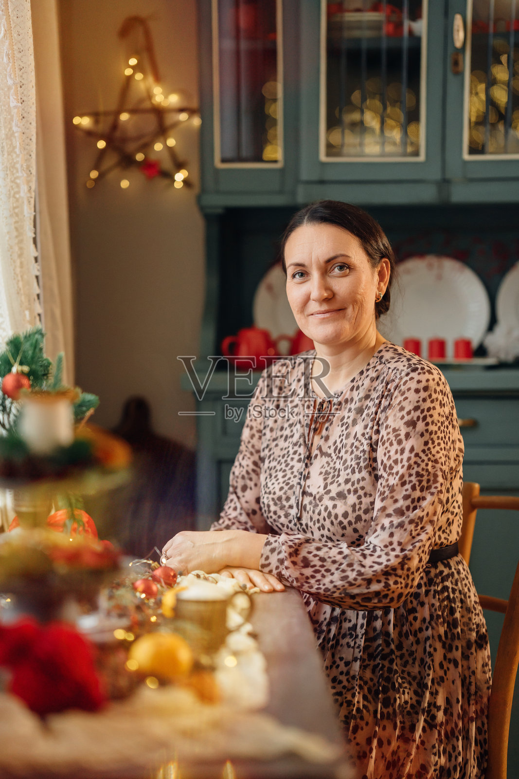 中年女性在节日的新年餐桌旁。照片摄影图片