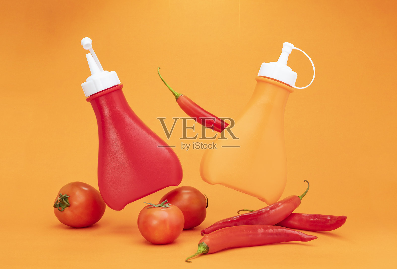 辣椒酱与番茄酱，塑料调料瓶孤立在黄色背景上照片摄影图片