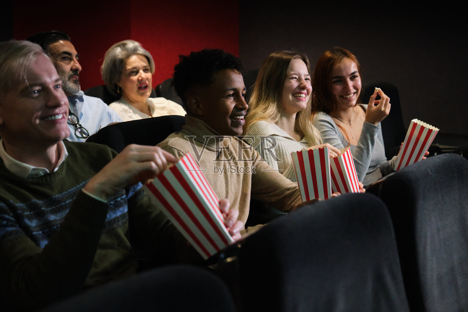 朋友们在电影院享受电影和吃爆米花照片摄影图片