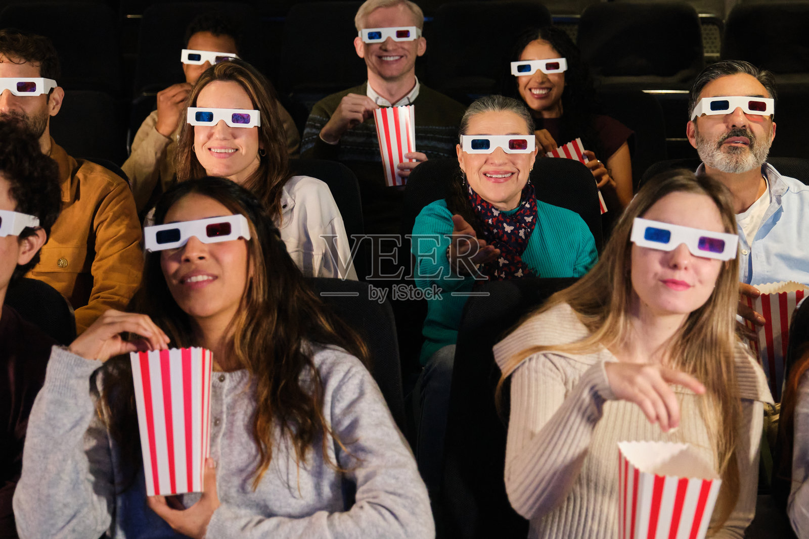 一群人在电影院享受3D电影，吃着爆米花，戴着3D眼镜。照片摄影图片