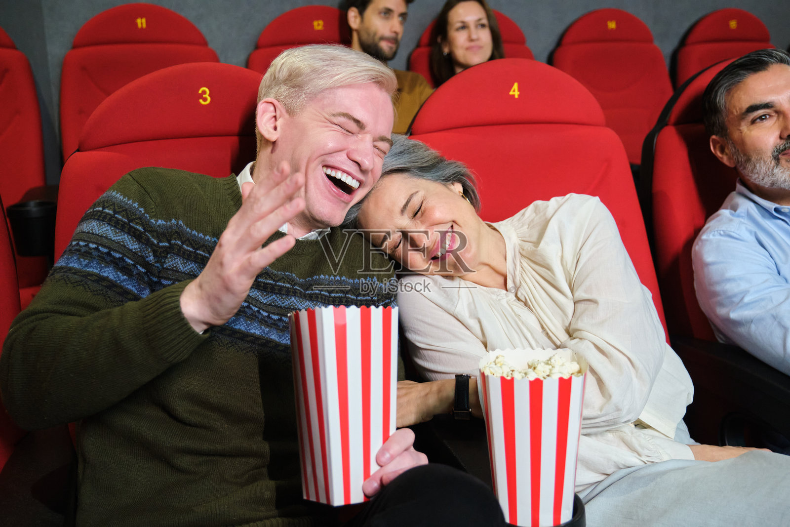 成熟夫妇在电影院享受电影，开心地吃着爆米花照片摄影图片