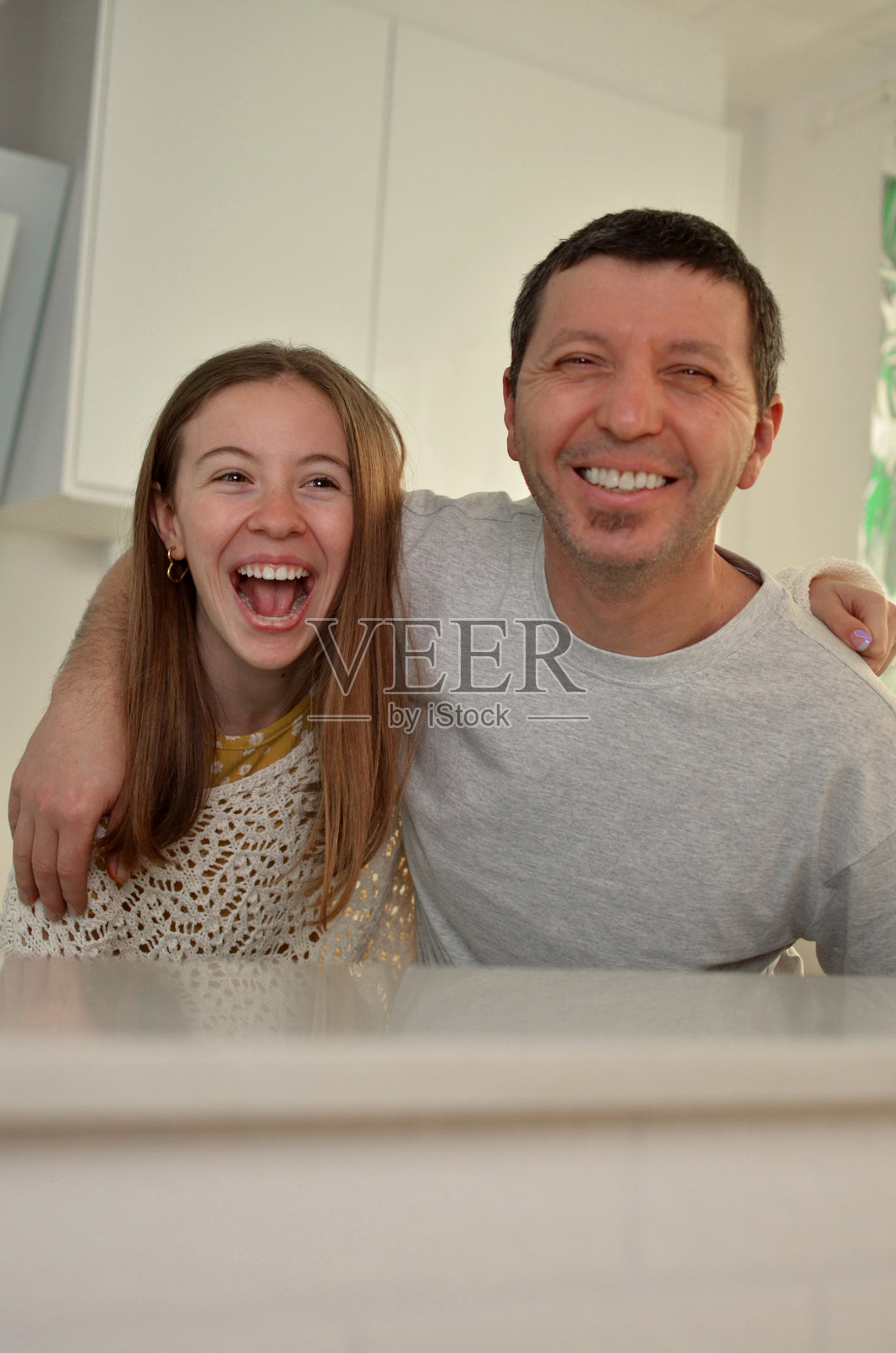 父亲和女儿在厨房里共享欢笑照片摄影图片