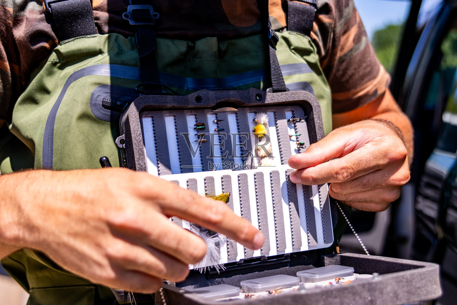 渔夫在飞钓盒中挑选人造苍蝇照片摄影图片