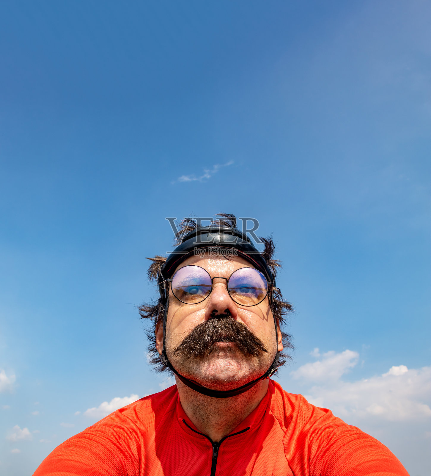 一名骑自行车的人在蓝天下戴着复古头盔骑行。照片摄影图片