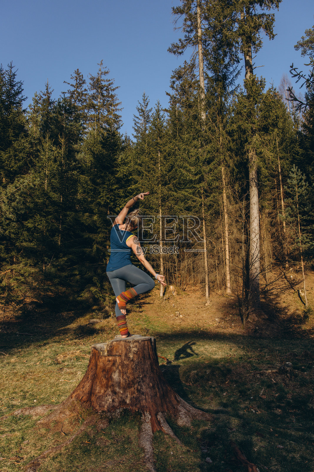 身材健美、快乐的年轻女性穿着运动服，在阳光明媚的早晨的自然公园中冥想、做瑜伽、呼吸和拉伸练习。真实自然的照片。照片摄影图片