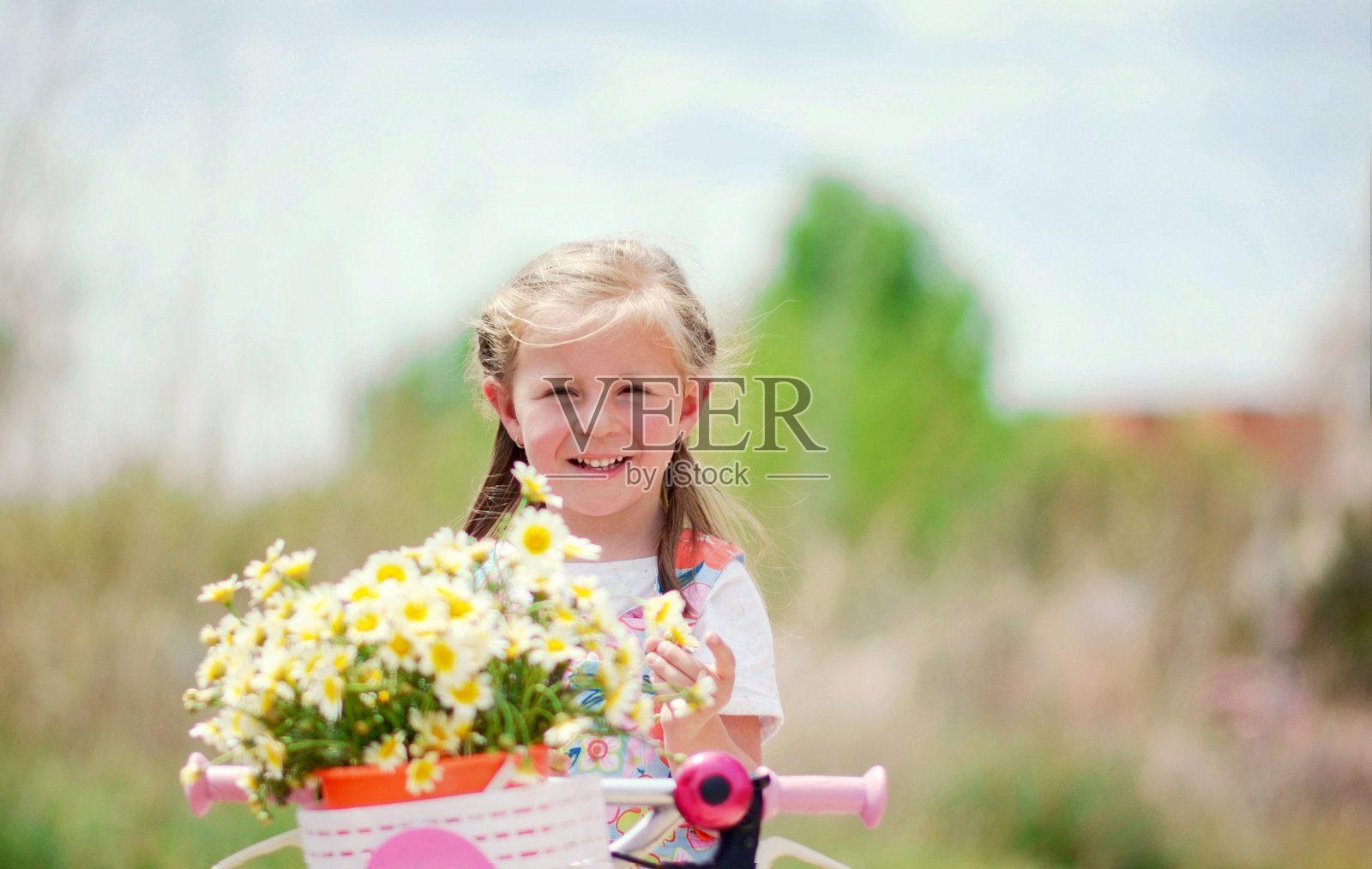 微笑的孩子骑着装有花篮的自行车照片摄影图片