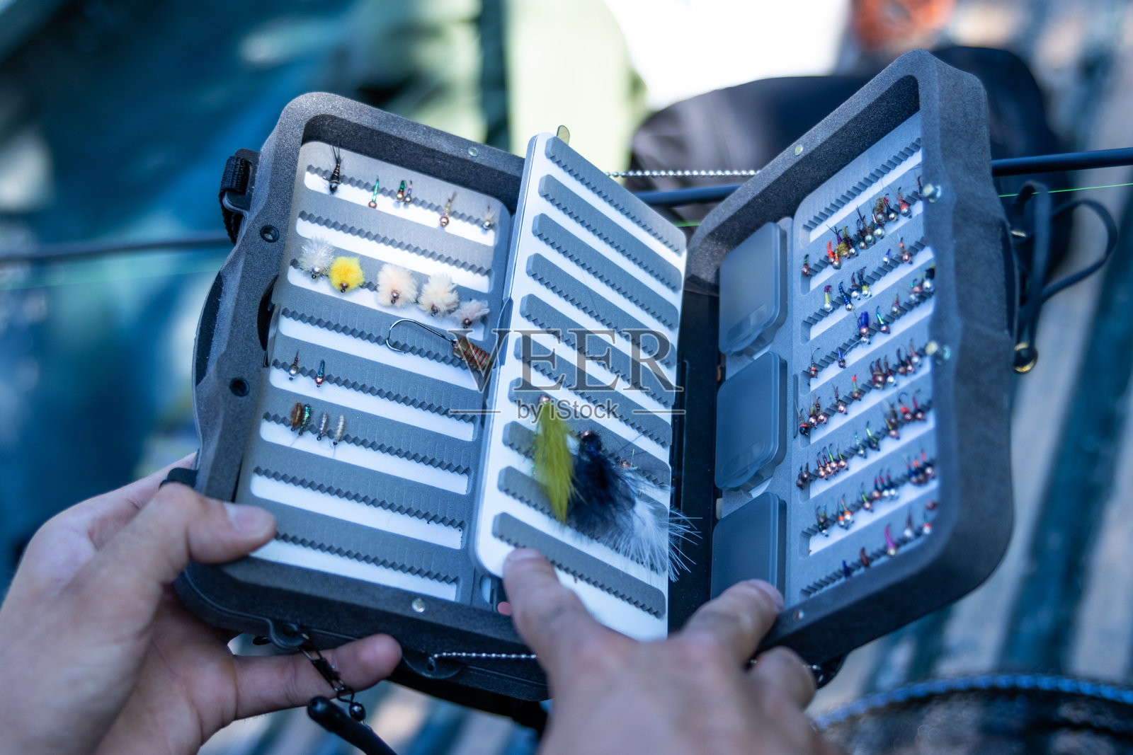 渔夫从钓具箱中挑选人造苍蝇进行飞蝇钓鱼照片摄影图片