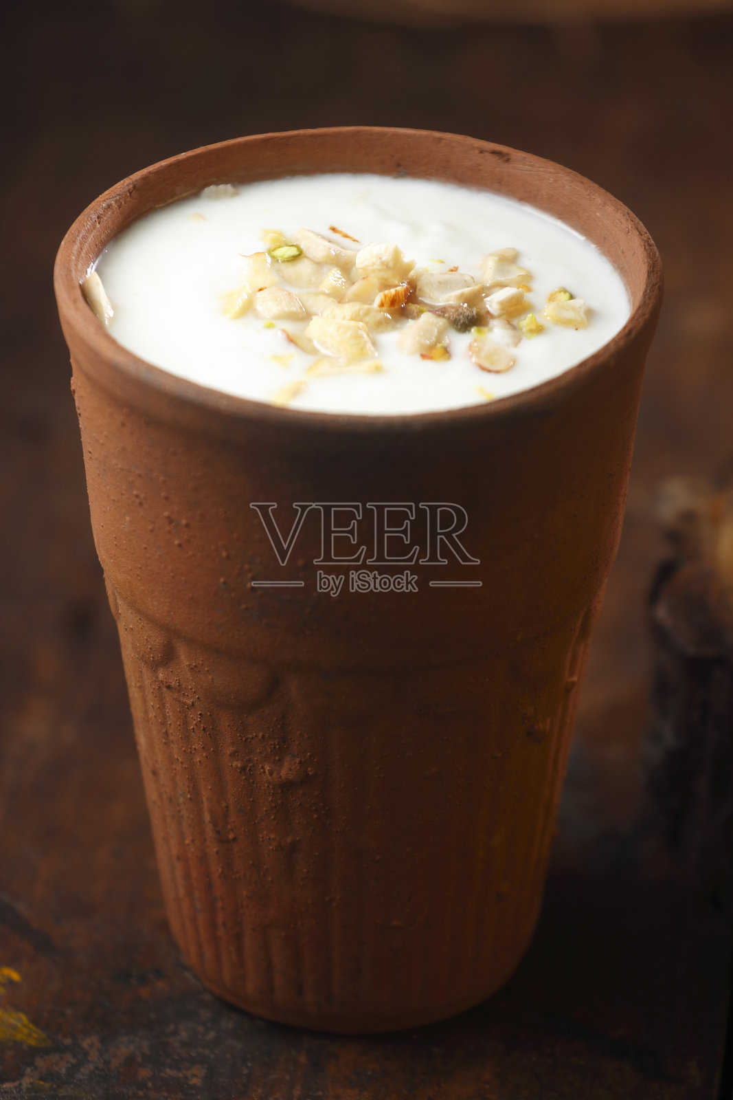 陶杯中的拉西饮料，上面撒有干果照片摄影图片