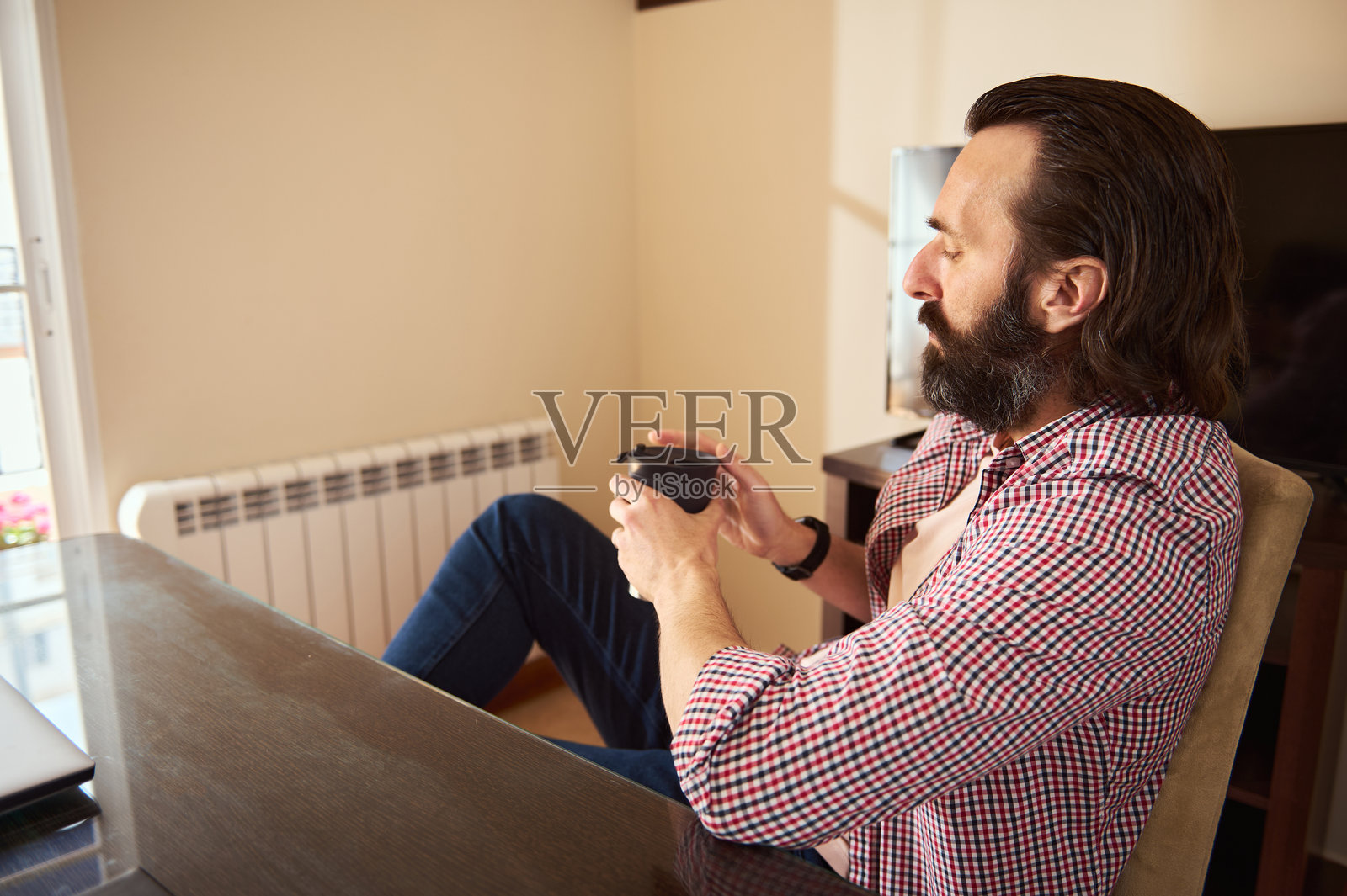 现代家居办公室中，男人悠闲地坐在桌前喝咖啡照片摄影图片