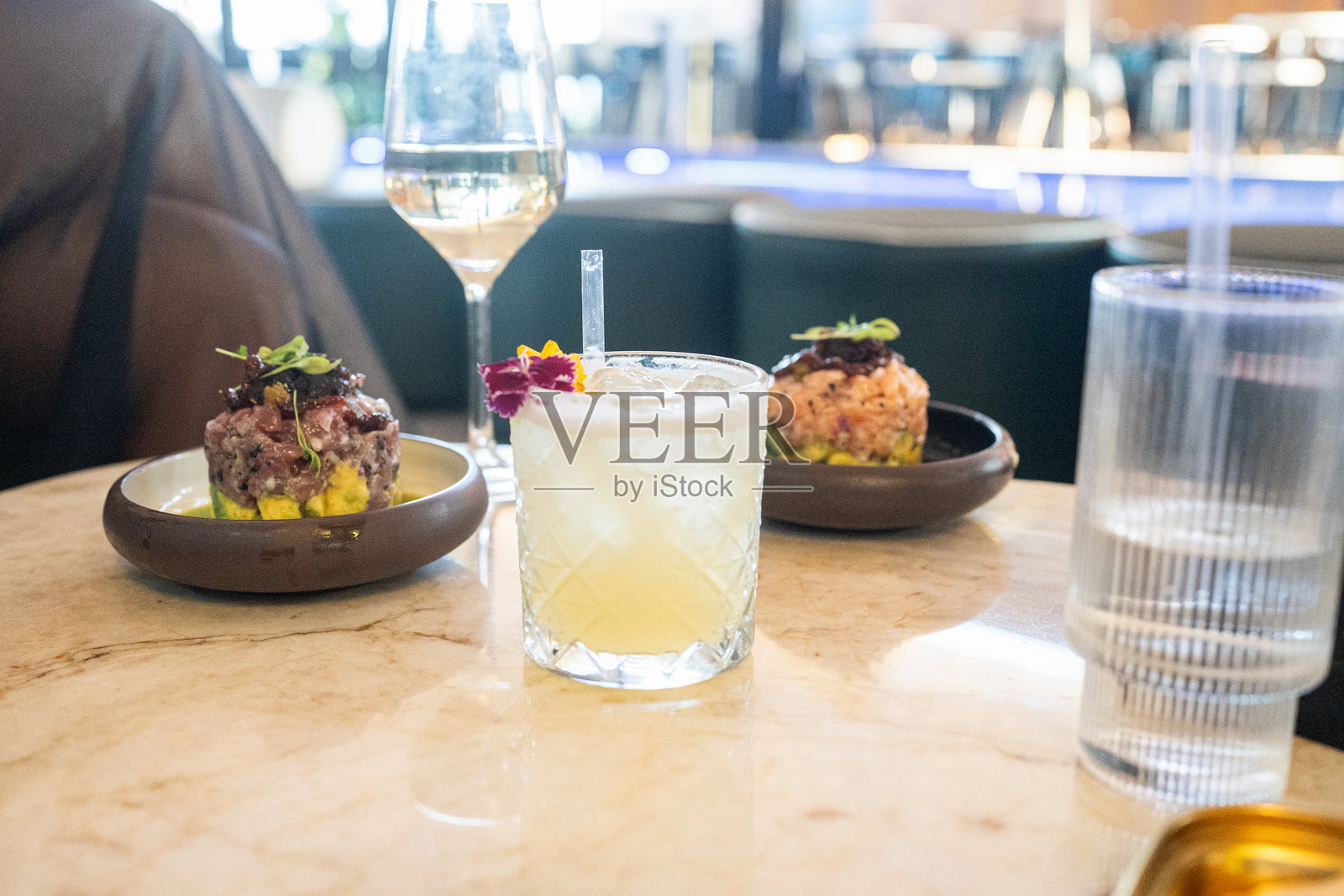 大理石桌上的花卉鸡尾酒与金枪鱼和三文鱼塔塔照片摄影图片