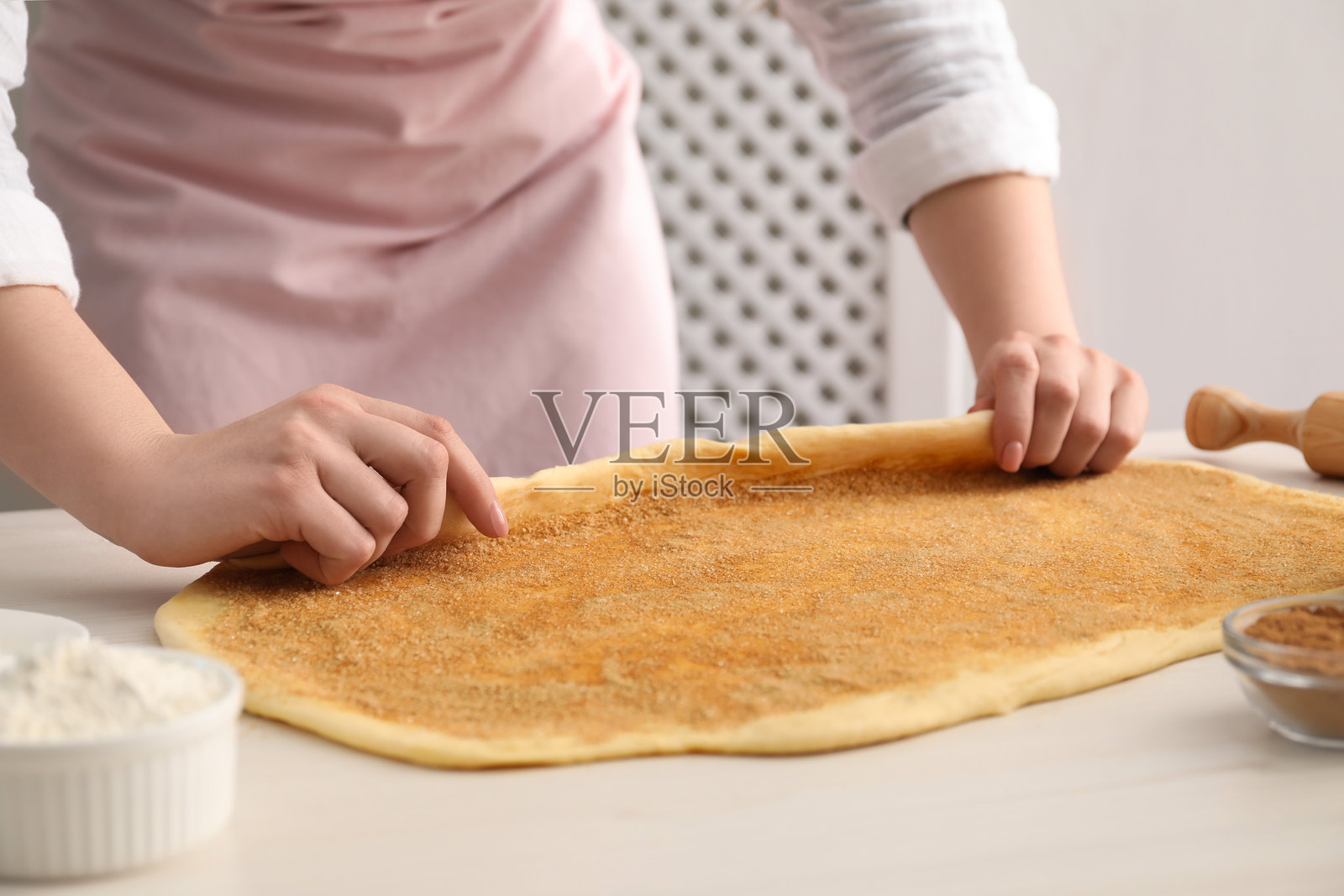 制作肉桂卷。女人在白色桌子上塑形面团，特写镜头。照片摄影图片