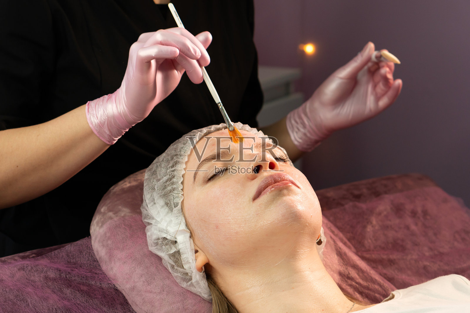 美容师在水疗中心为客户的额头涂抹保湿面膜照片摄影图片