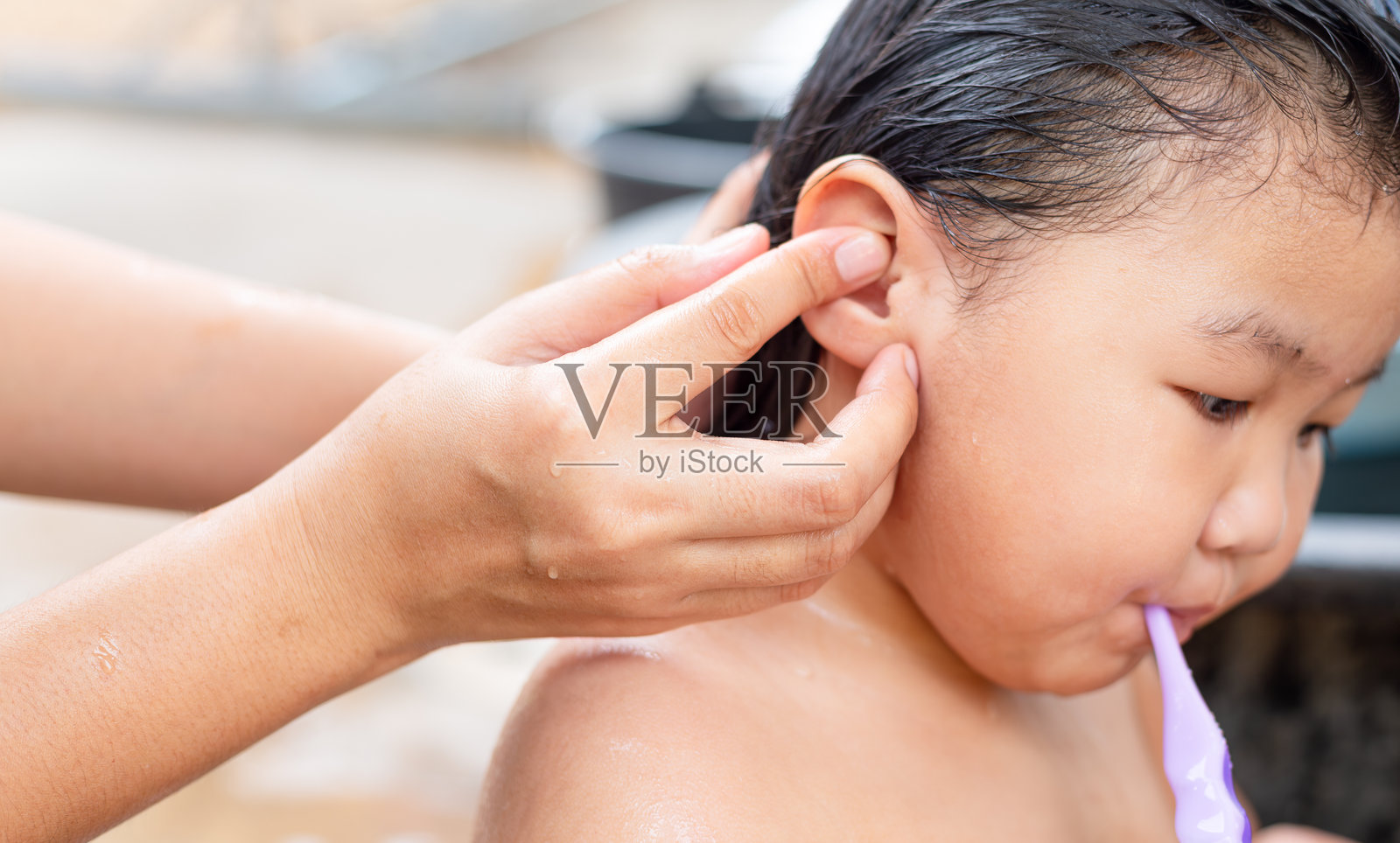 母亲的手正在给她的小女儿洗澡，亚洲小女孩在泡泡浴中，单身母亲温柔地给女儿洗澡，女儿的脸和身体上满是泡泡。照片摄影图片