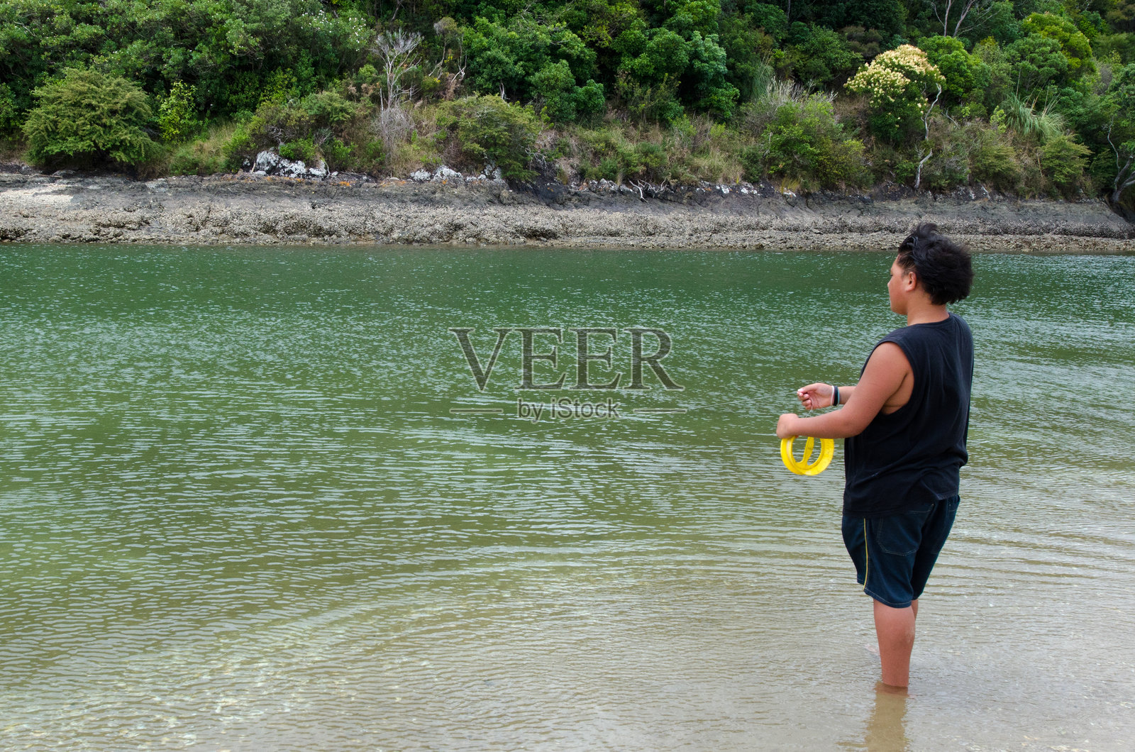 年轻的毛利男子在新西兰的一条河里钓鱼照片摄影图片