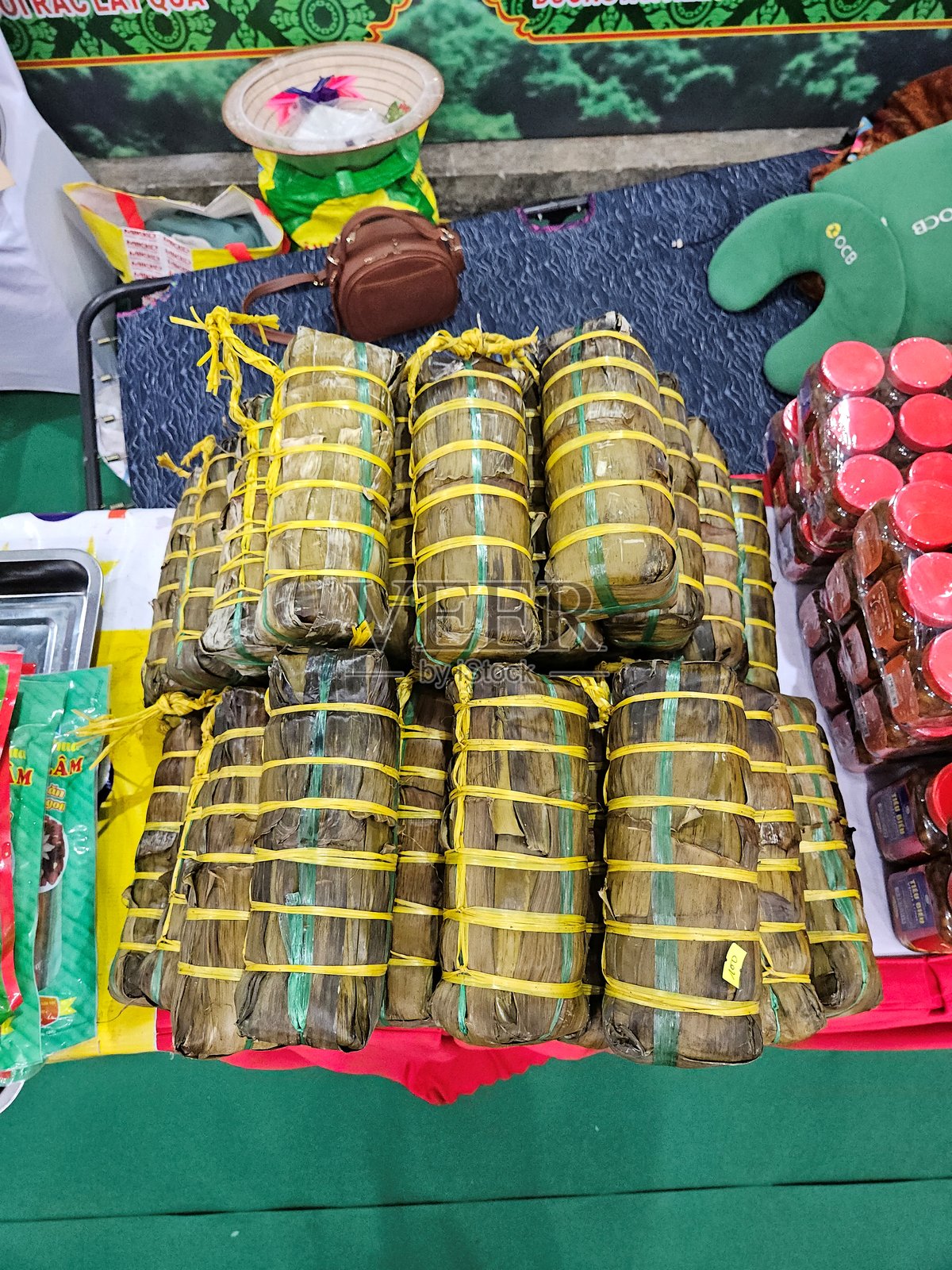 一堆传统越南圆形米糕用香蕉叶包裹，并用黄色绳子系紧，陈列在市场的桌子上。照片摄影图片
