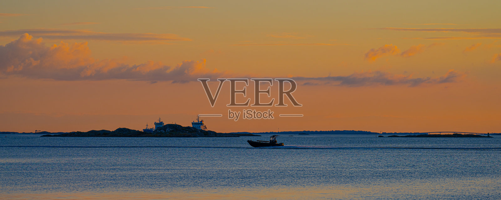 水面上的日落与一只行驶中的船。照片摄影图片