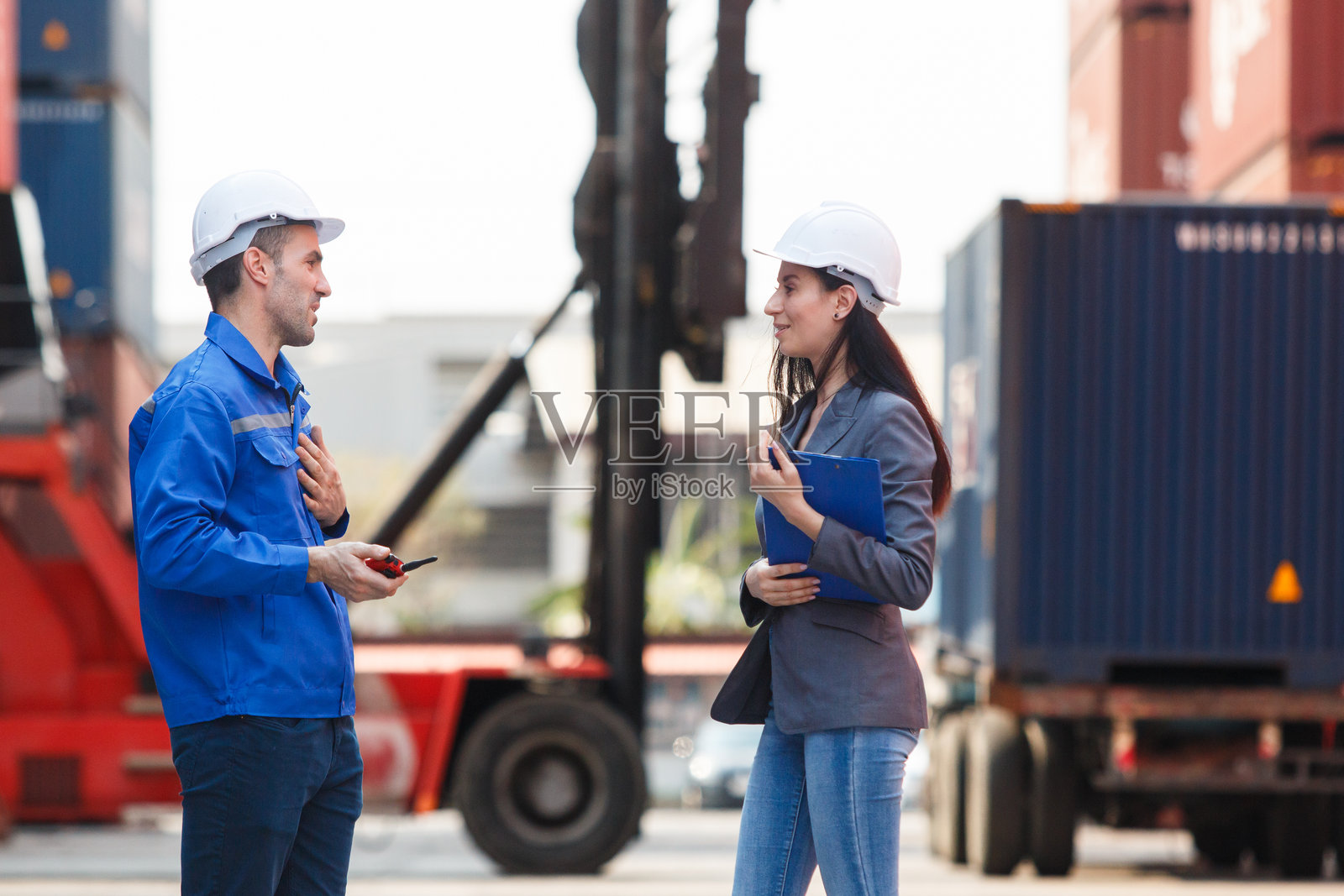 女商人与物流或船厂工程师在集装箱场进行讨论或商务洽谈。照片摄影图片