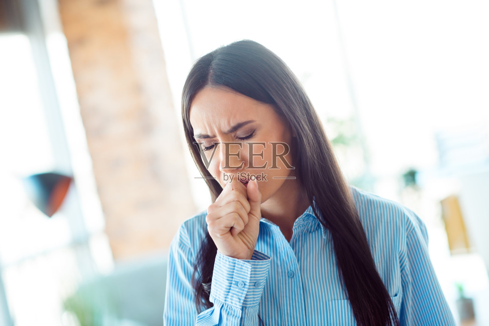 年轻专业人士在日光办公室环境中咳嗽，表现出疾病与健康的情感照片摄影图片