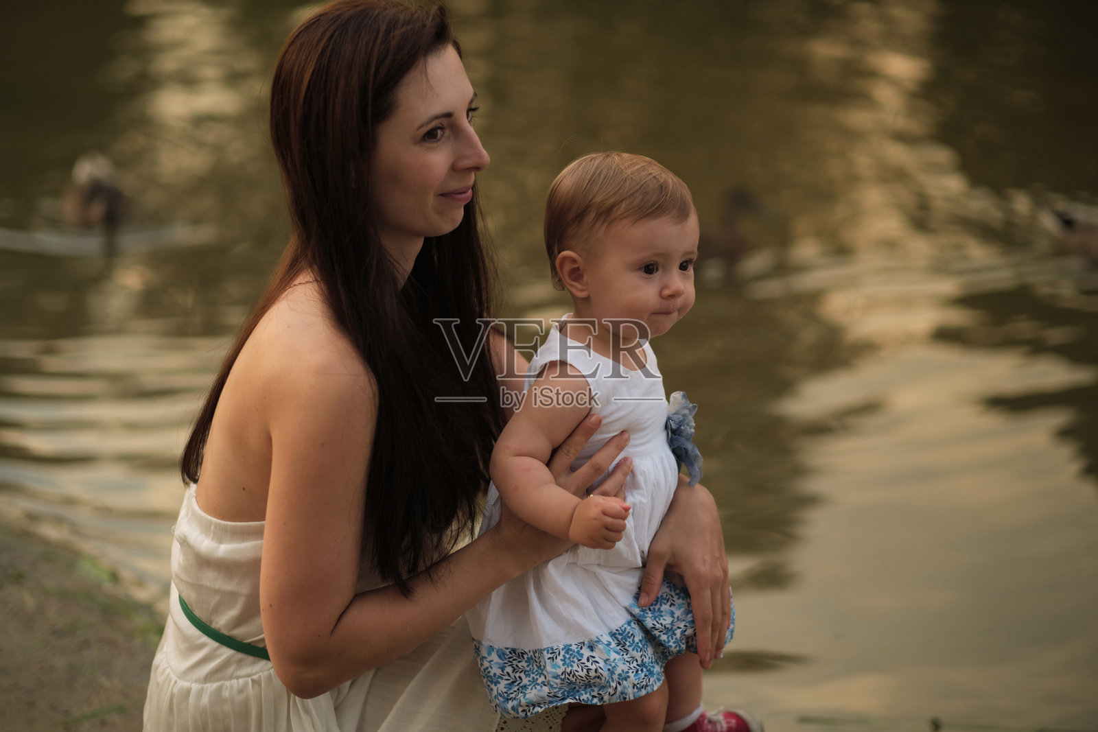 母亲在黄昏的怀抱中支持她深思的孩子。这是一幅充满关爱与反思的画面。照片摄影图片