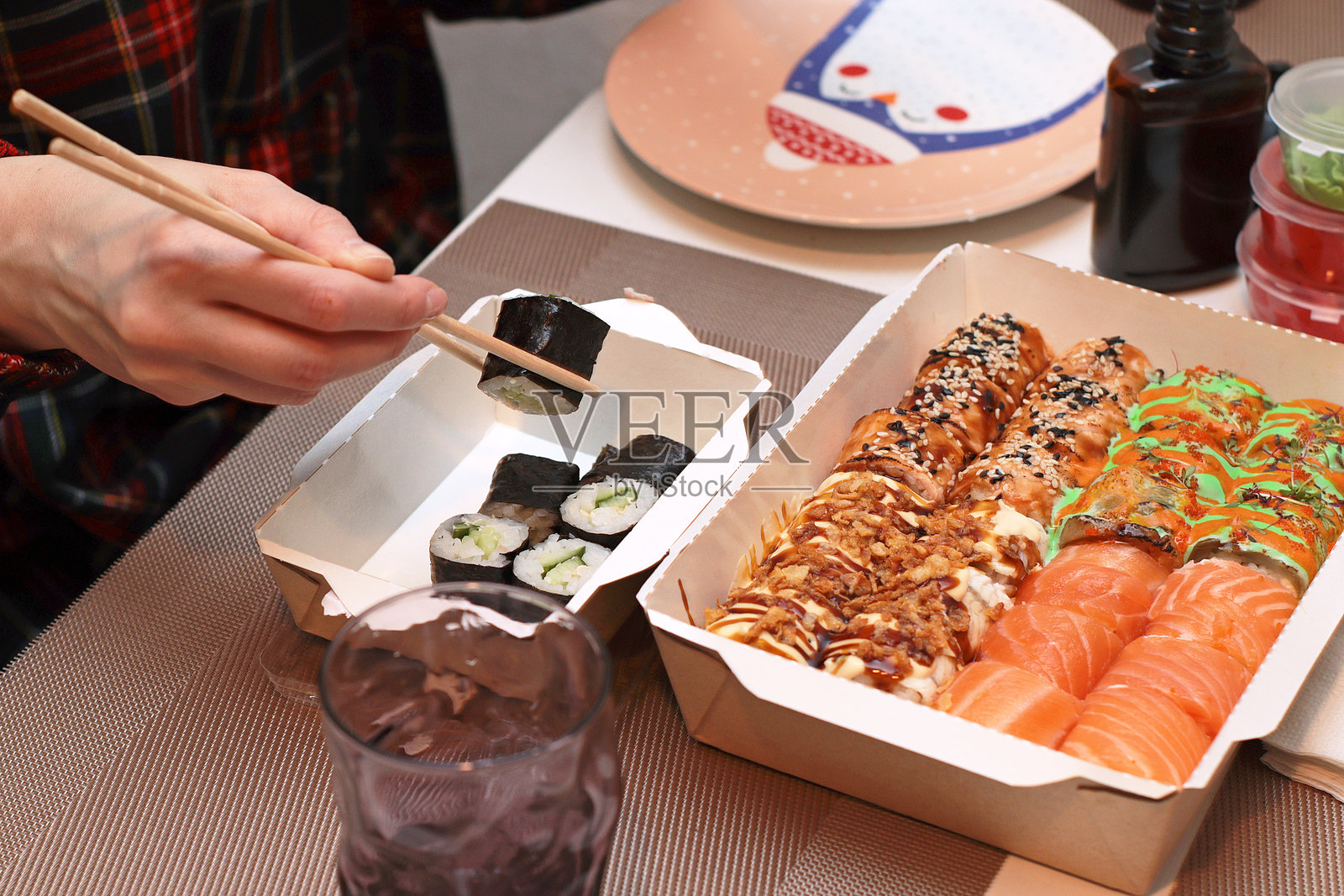 一幅诱人的俯视图，精美的寿司卷优雅地摆放在桌子上。纤细的手握着筷子，展示了用餐的艺术。旁边，餐巾和调味酱增添了美味的氛围。照片摄影图片