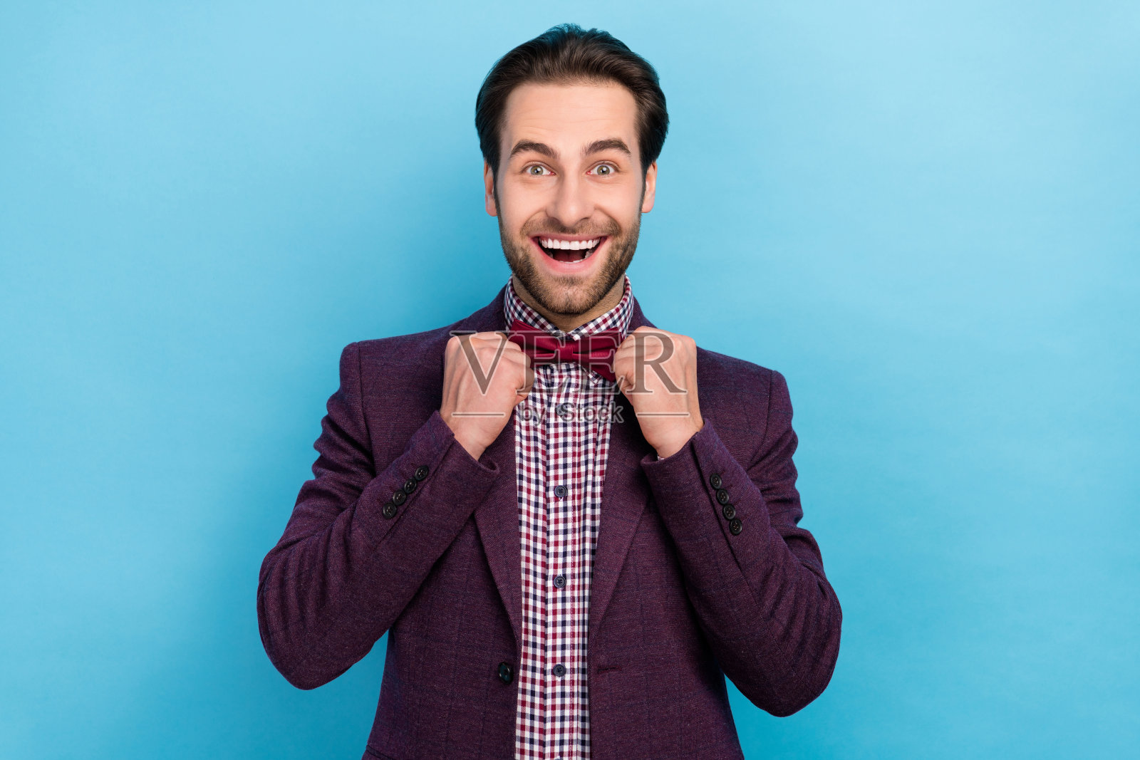 吸引人的疯狂男演员在蓝色背景下调整领结，准备上台表演照片摄影图片