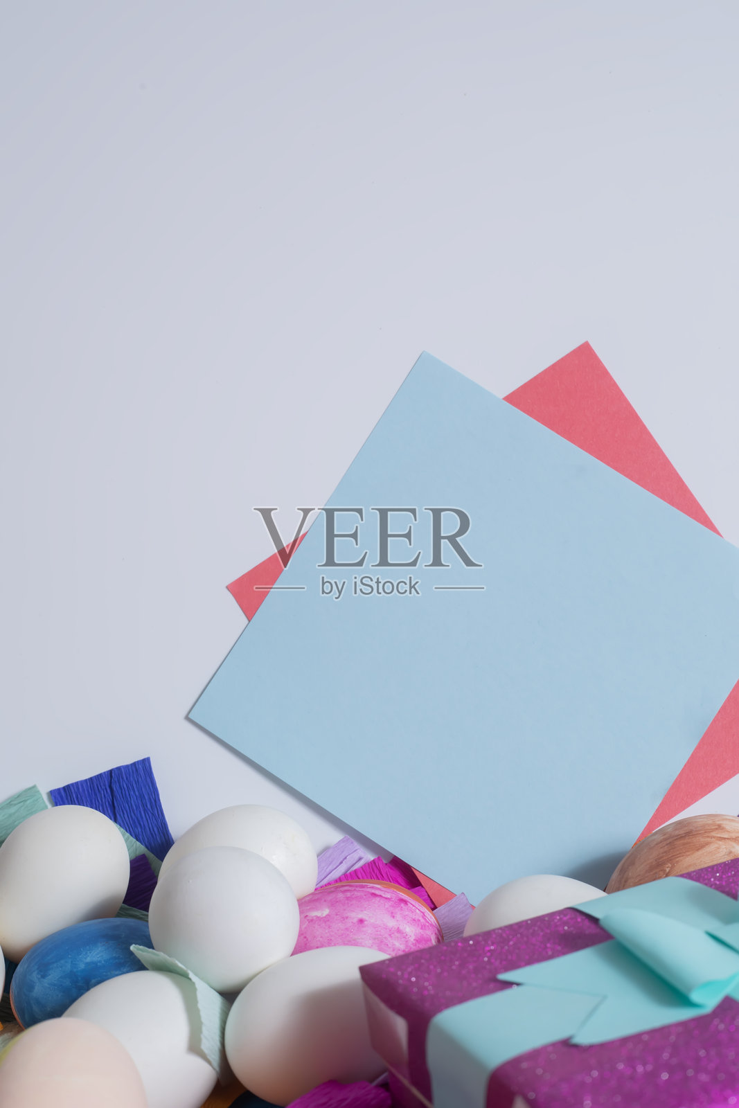 五彩纸背景上的复活节彩蛋和白色背景上的空白卡片。照片摄影图片