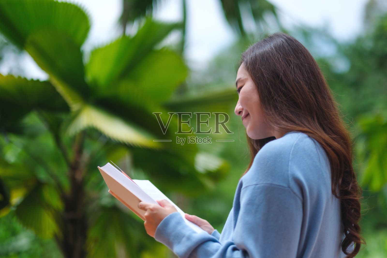在花园里阅读书籍的女性肖像图照片摄影图片