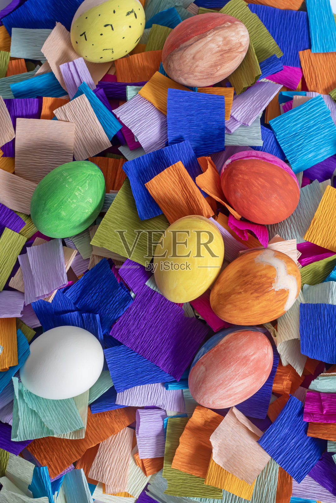 五彩缤纷的复活节彩蛋在鲜艳的绉纸装饰背景上，俯视图照片摄影图片