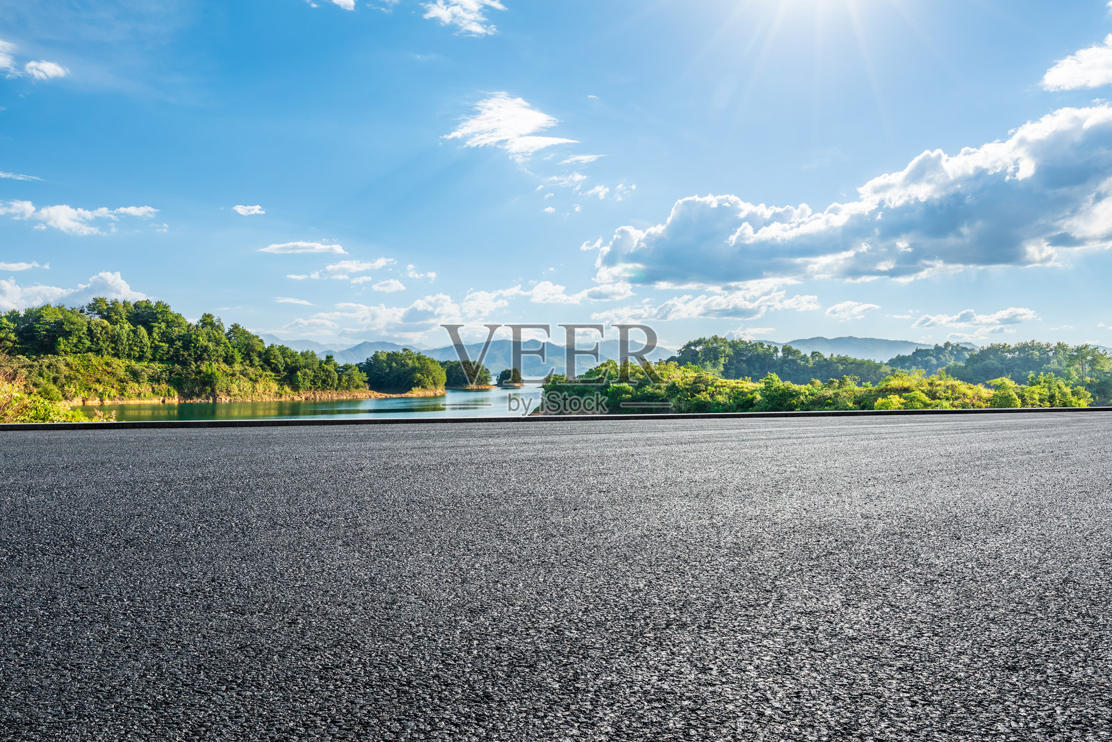 夏季的沥青公路旁有蓝色湖泊和绿色山丘照片摄影图片