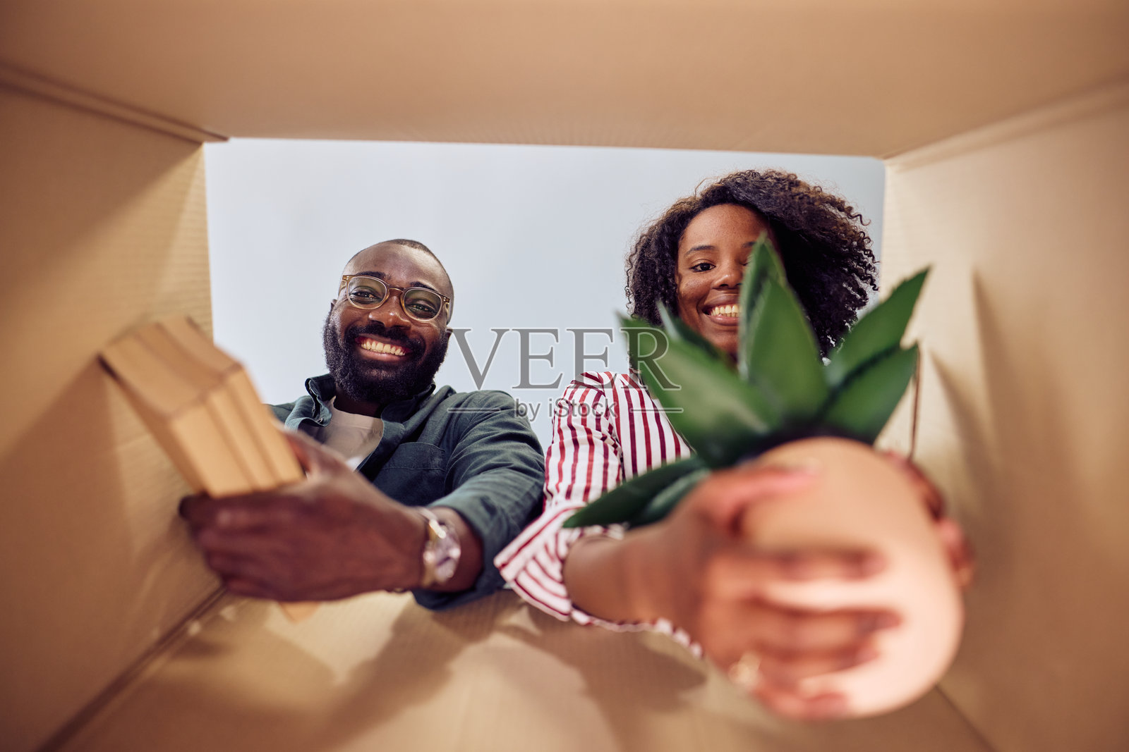 快乐的情侣在新家中从纸箱中拆 unpack 物品照片摄影图片