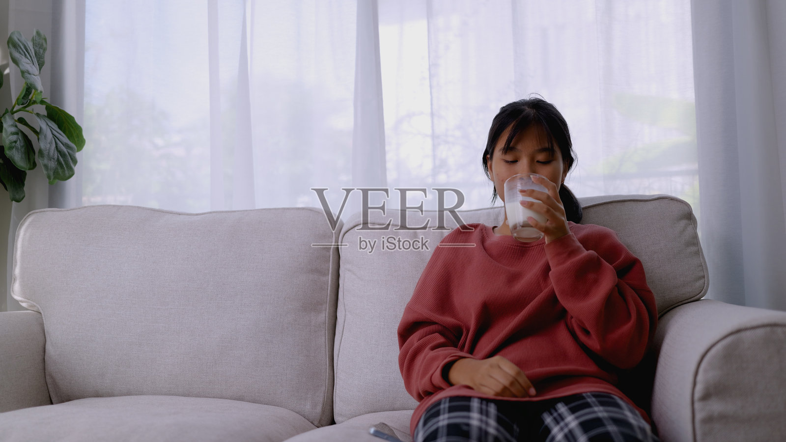 健康的早晨开始 – 一位肤色黝黑的亚洲女孩享用一杯牛奶。4k照片摄影图片