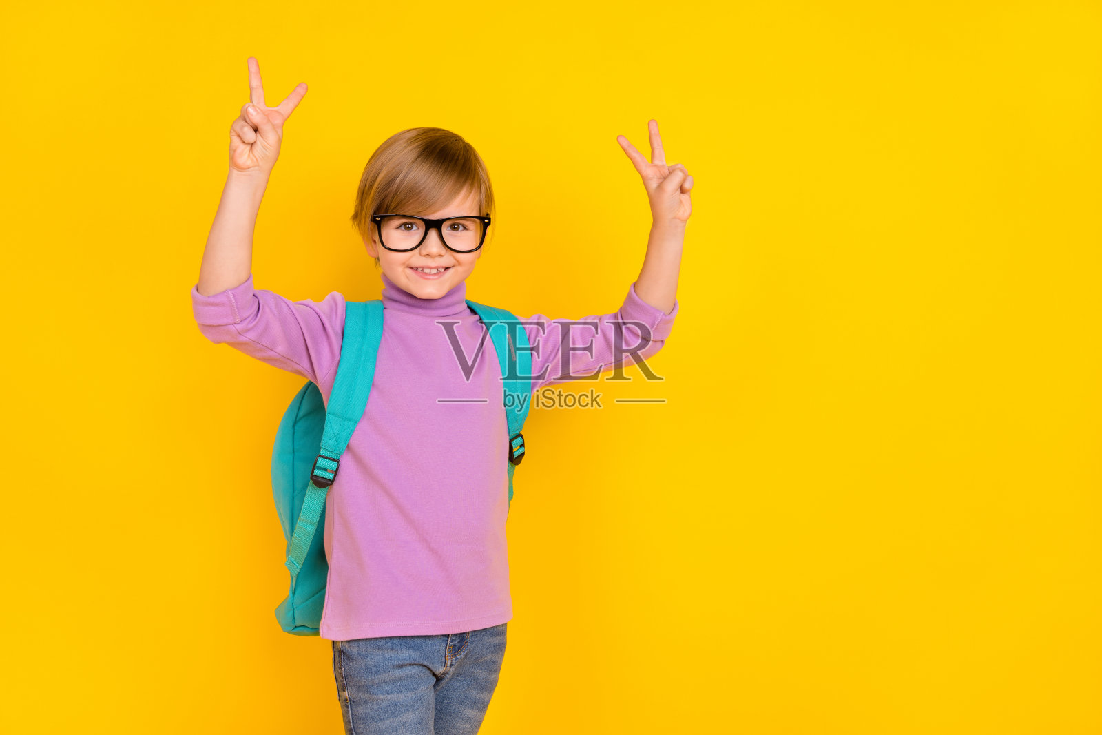 可爱的小男孩穿着休闲服，做出V字手势，准备在9月1日上学，背景为黄色。照片摄影图片