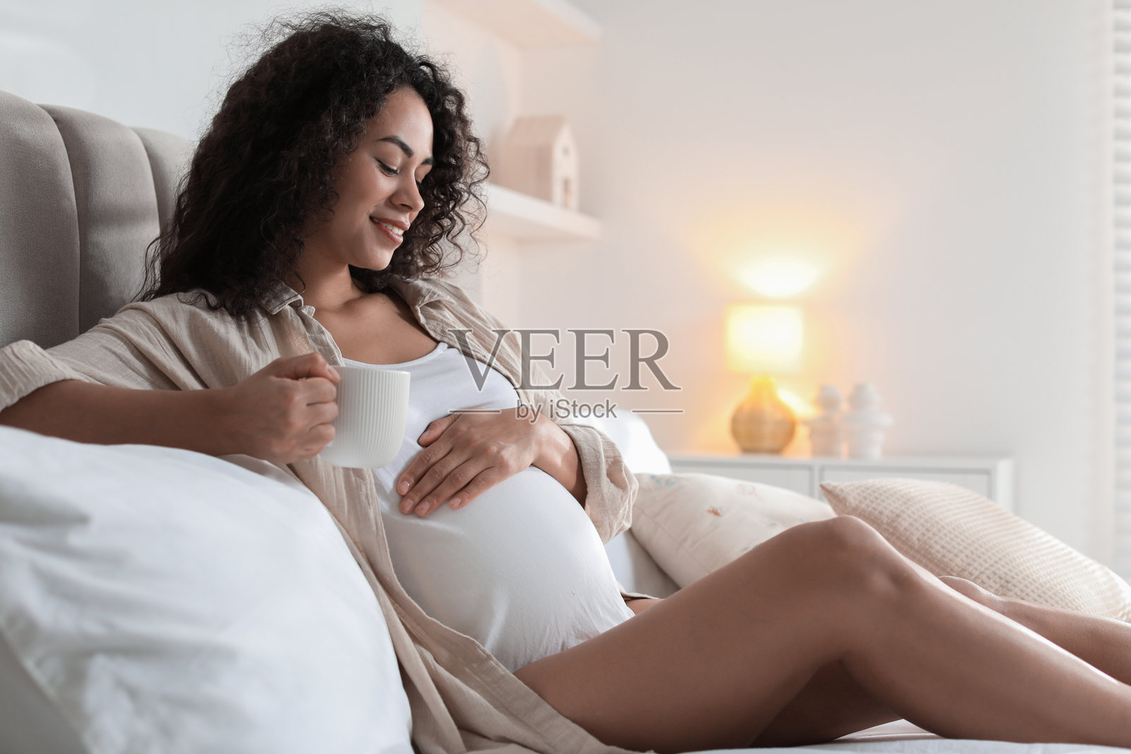 美丽的孕妇在家床上拿着饮品的肖像照片摄影图片
