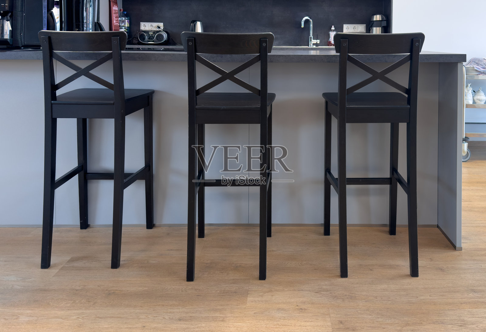 三把高高的黑色木制吧台椅靠近厨房岛台照片摄影图片