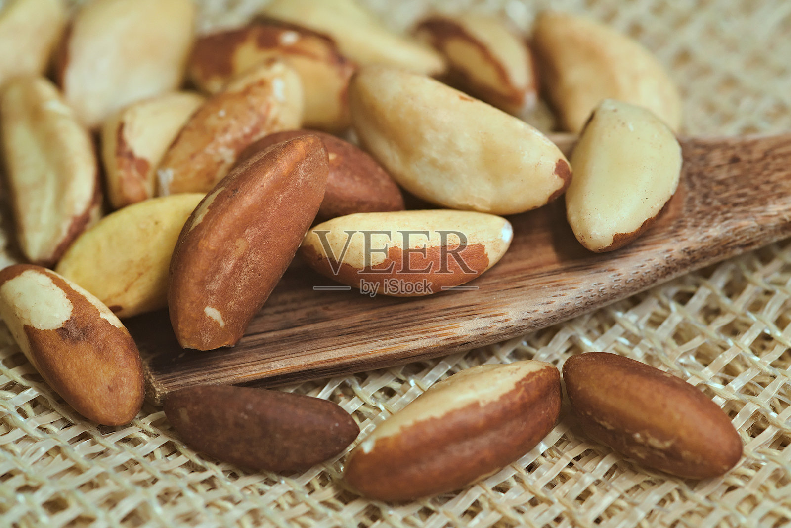 巴西坚果，来自亚马逊的出口产品。巴西坚果放在粗犷的表面上，旁边有一把木勺。巴西食品照片摄影图片