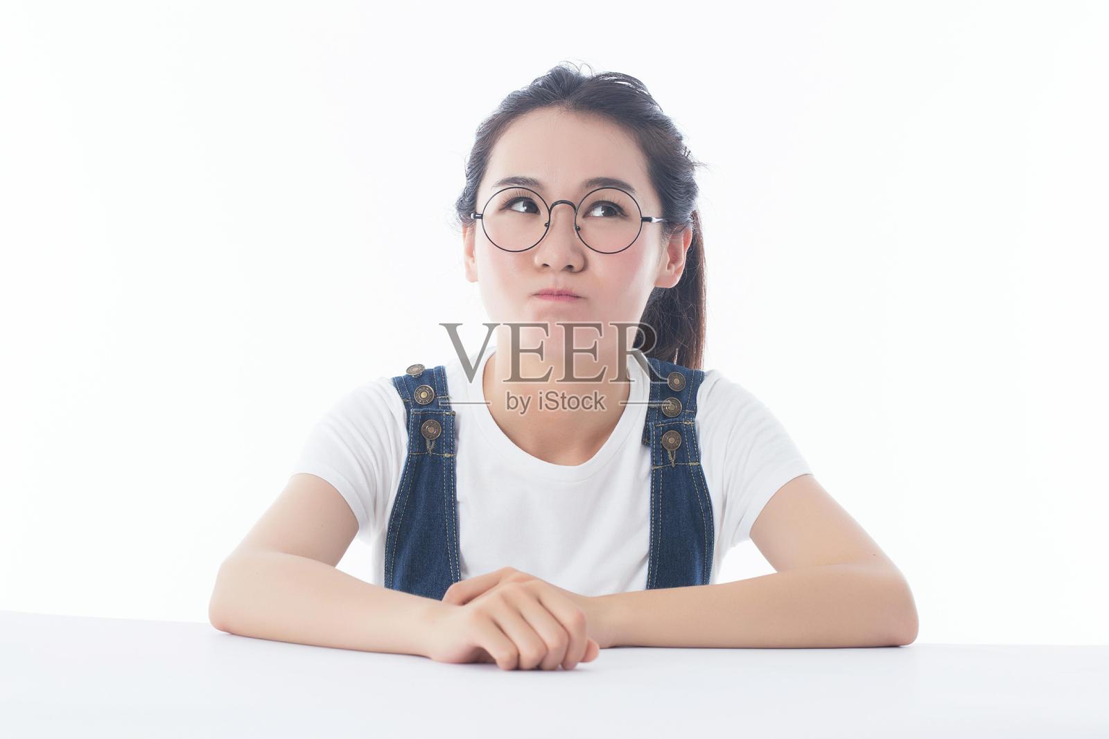 一位戴眼镜的年轻女性正在仰望并思考。照片摄影图片