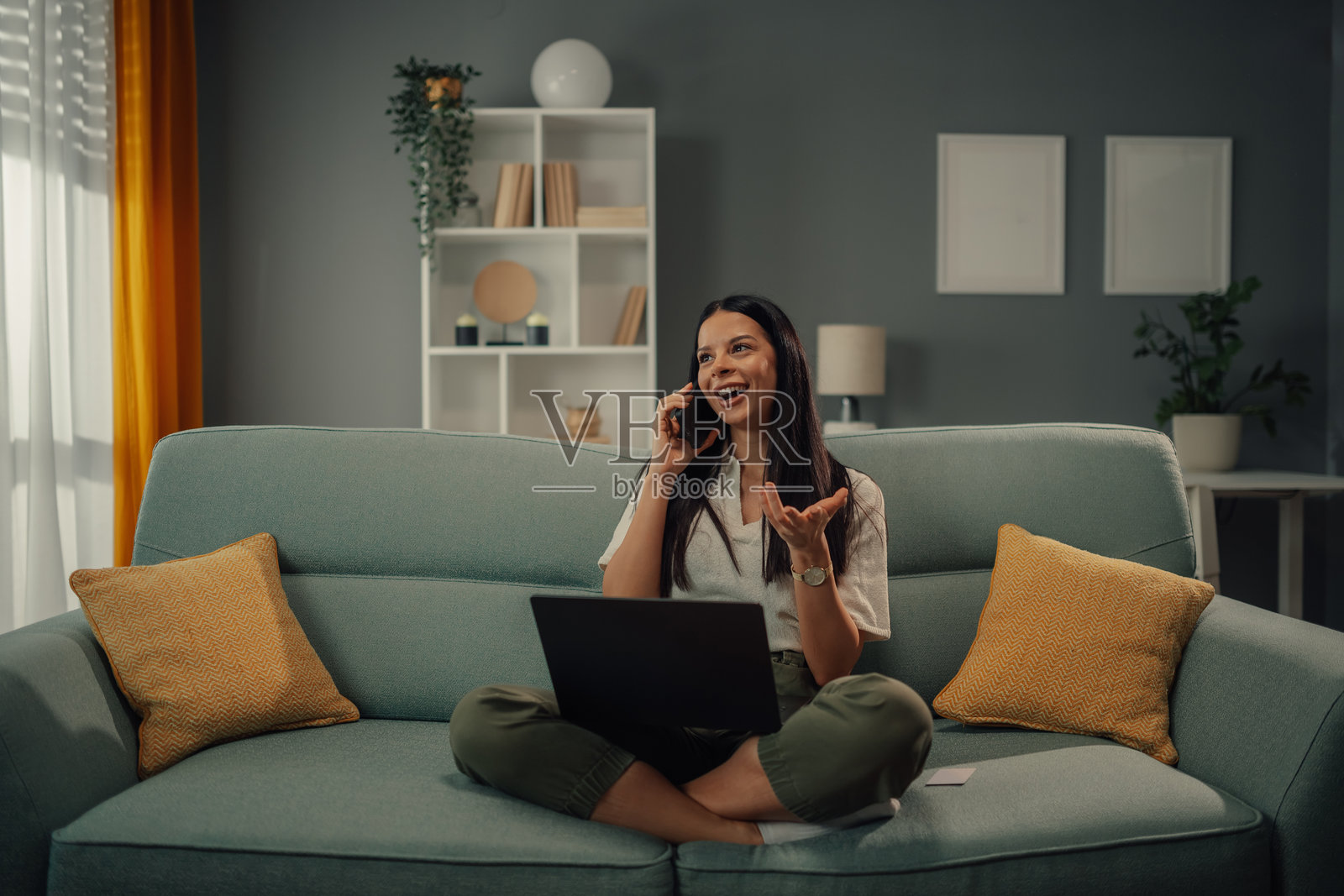 年轻女性在沙发上用笔记本电脑和手机远程工作照片摄影图片