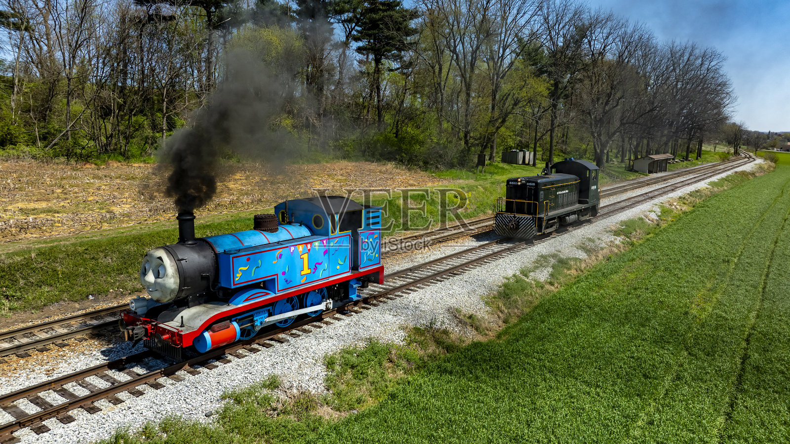 春季风光中色彩斑斓的托马斯蒸汽机车和柴油机车在乡村轨道上行驶照片摄影图片
