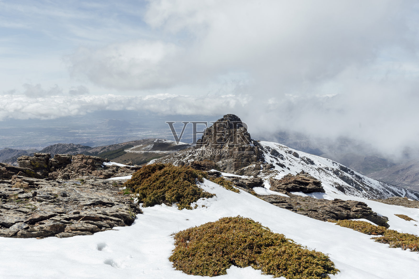 巍峨的岩石山峰耸立在内华达山脉之上，雪和云彩在地平线上升起照片摄影图片