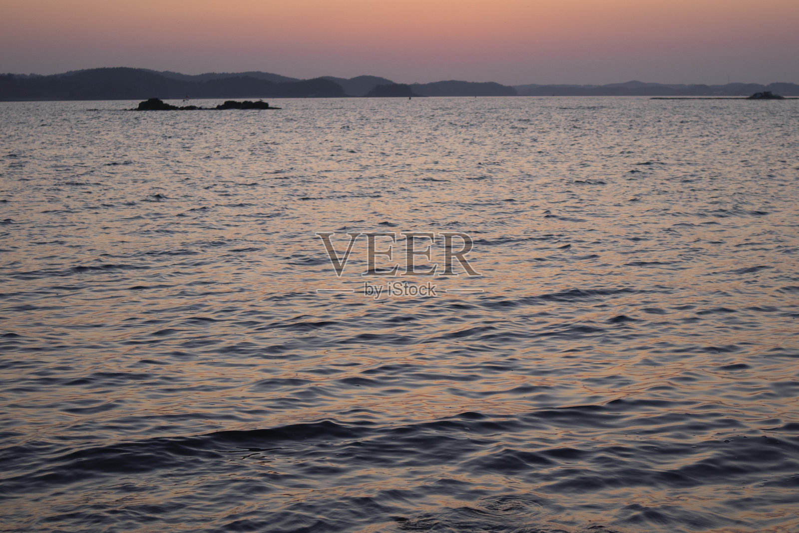 这是一个傍晚的海面，映衬着美丽的红色日落。照片摄影图片