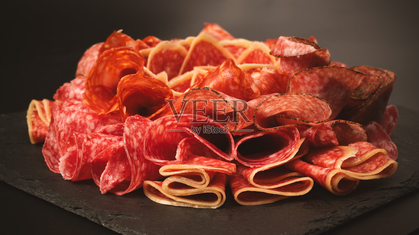 不同种类的肉类切块放在砧板上。照片摄影图片