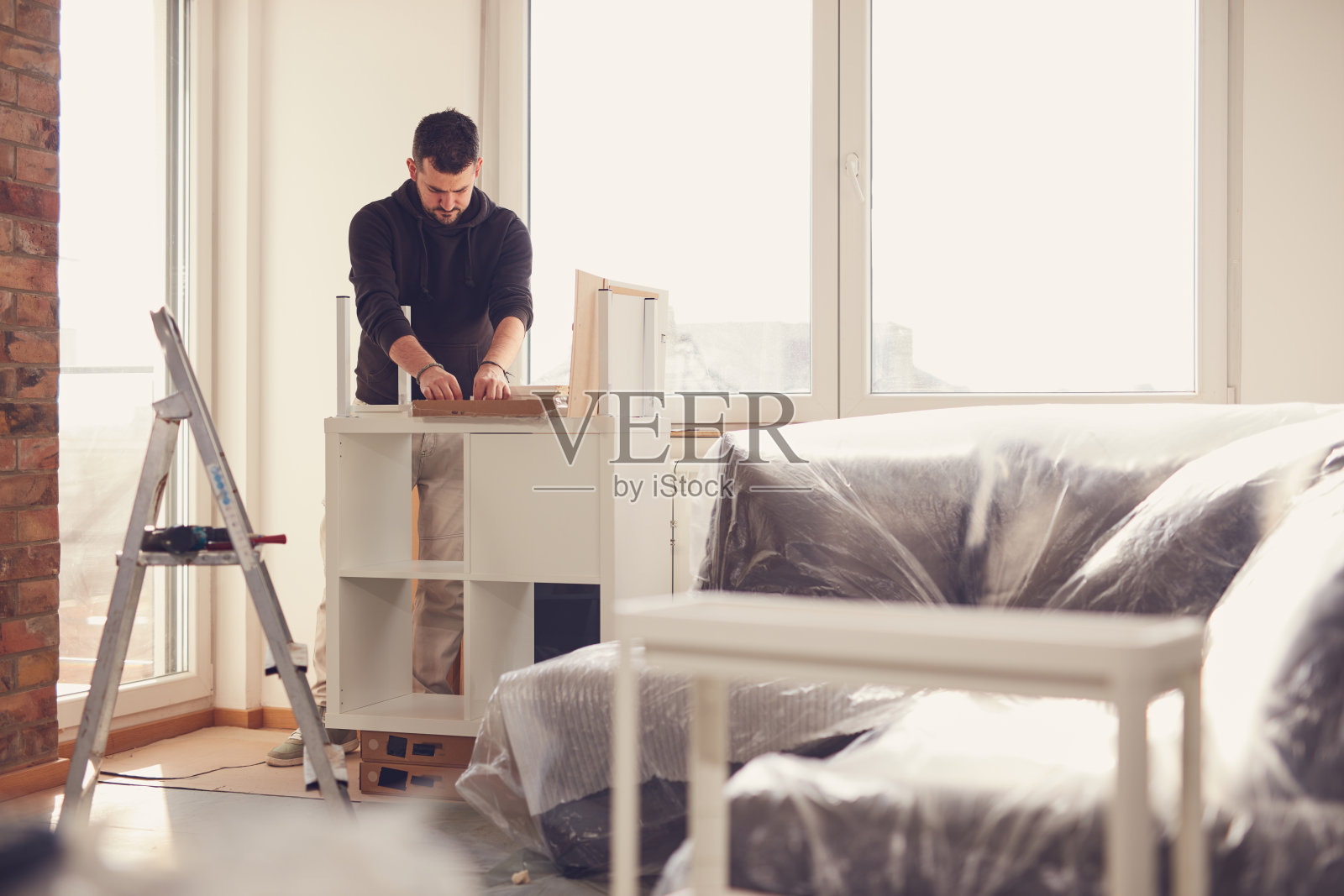 男子在新公寓里工作并组装家具。照片摄影图片
