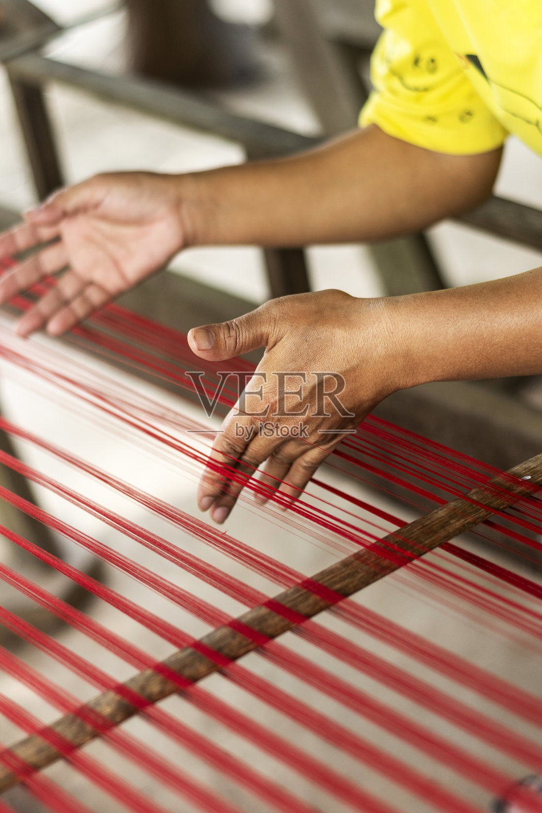 工人手部特写，展示传统天然丝绸制作机的丝线照片摄影图片